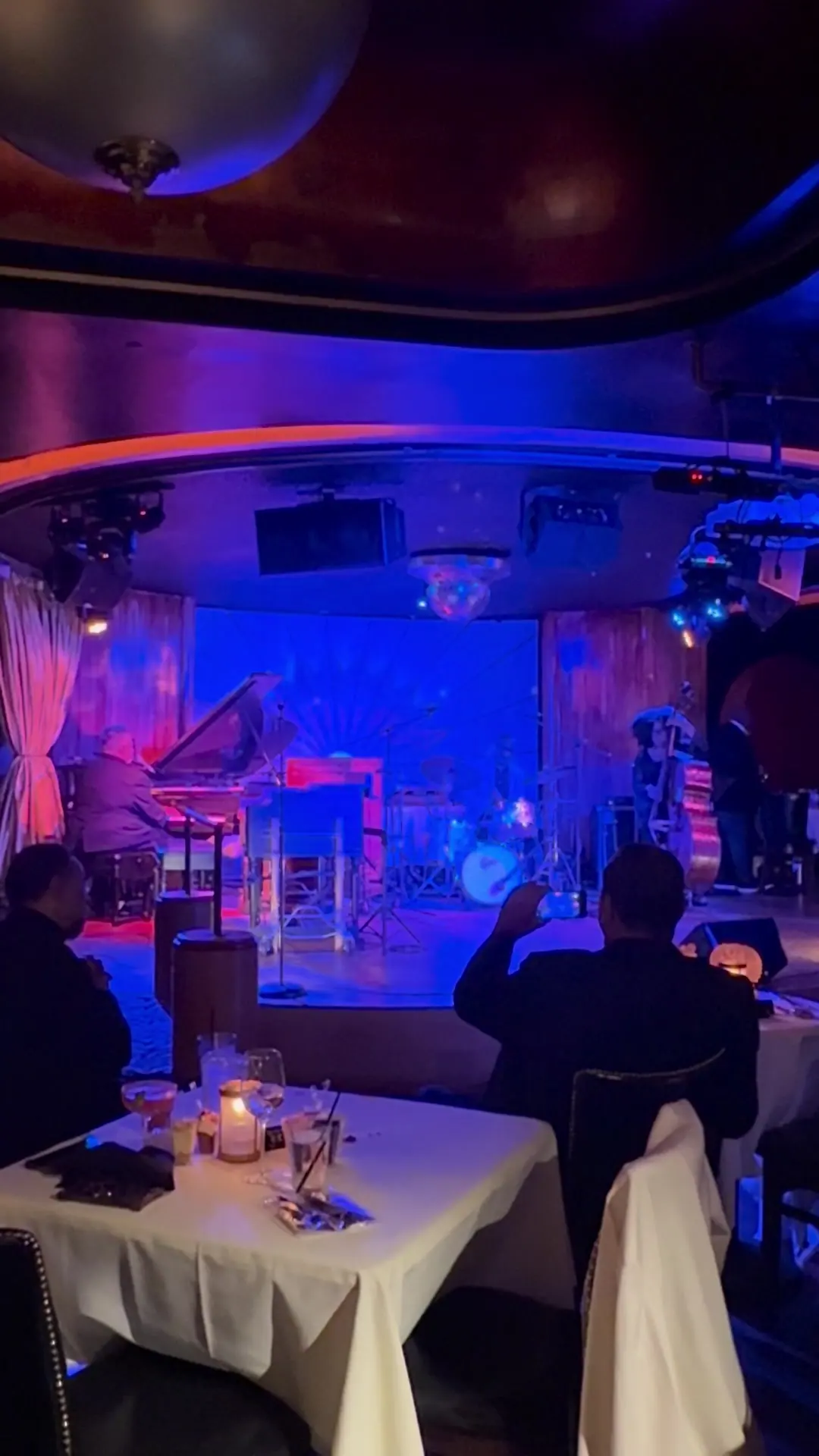 Candlelit tables set with white linen facing the stage at Cliff Bell's