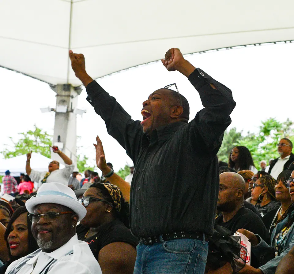 A guest throws both arms in the air mid-show